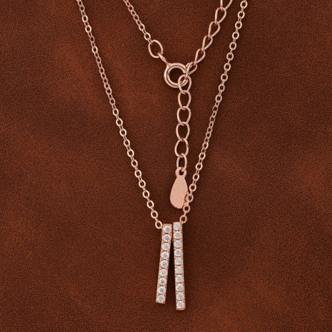 Two rose-gold chains with twin pavé bar pendants on warm brown leather.