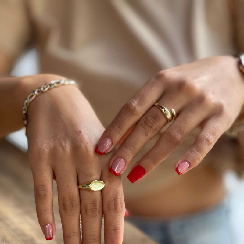 Close-up of hands on a wooden table showing a gold oval signet ring on the index finger.