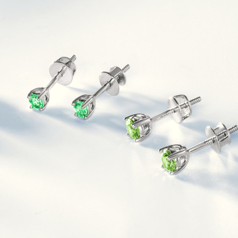 Green-stone solitaire studs in white-metal claws on white (cropped from a multi-colour stud line-up).