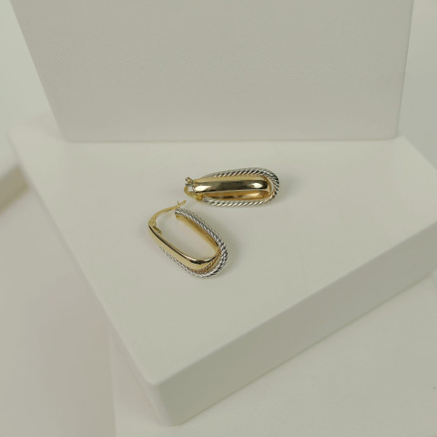 Two-tone oval hoops with a twisted cable section on white studio blocks.