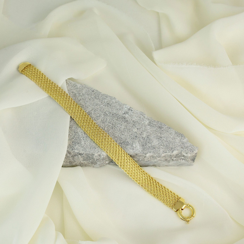The same gold mesh bracelet over a grey stone on cream silk.