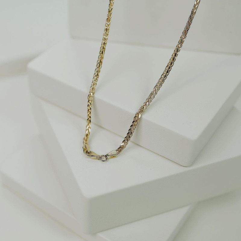 Gold box chain draped over white studio blocks.