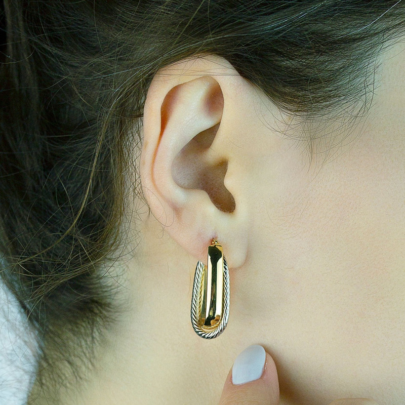 Ear wearing the same two-tone twisted oval hoop, hand at neck.