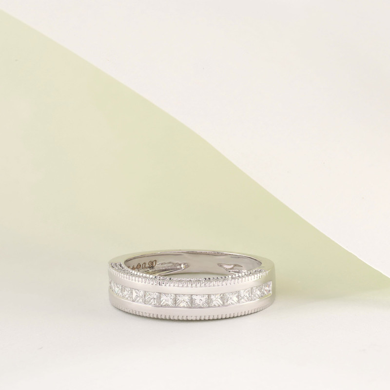 White-metal band with a channel of princess-cut stones between milgrain edges, on white.