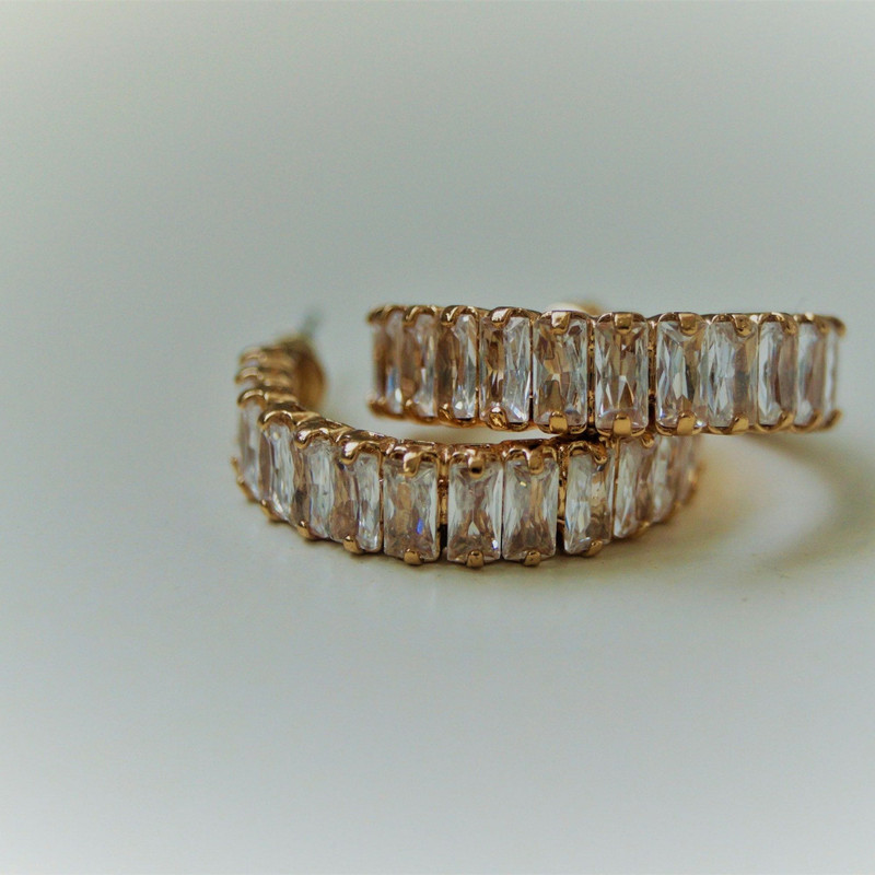 Two gold eternity bands set all the way round with baguette-cut stones, soft white-grey gradient.