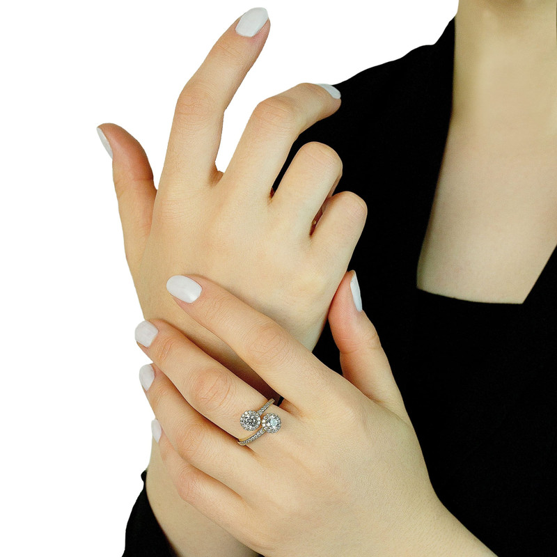 Hands on white studio background wearing the same gold two-stone halo ring.