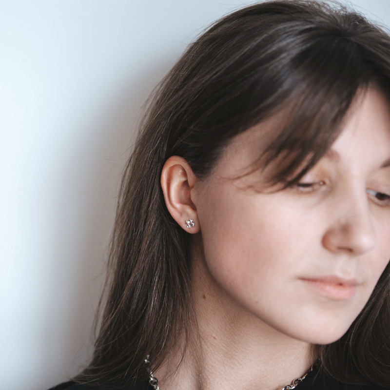 Woman in profile against a white wall wearing a tiny diamond stud.